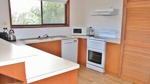 Een moderne keuken met een wit aanrecht, een roestvrijstalen waterkoker, een magnetron, een broodrooster en een inbouwoven.