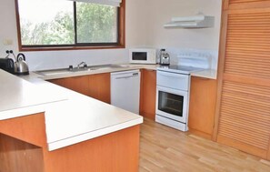 A modern kitchen with a white countertop, stainless steel kettle, microwave, toaster, and a built-in oven.