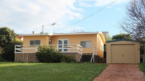 Einbungalow mit Vorgarten, Garage und einem kleinen, umzäunten Bereich.