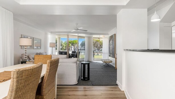 A modern living room with a sofa, wicker chairs, a dining table, and a small side table. - Byron Bay Accom - The Palms 4 - 54 Lawson Street (Byron Shire)