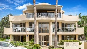 A multi-story building with balconies, a sign for Byron Bay Luxury Homes, and a sign indicating the address as 54 Palmers. - Byron Bay Accom - The Palms 4 - 54 Lawson Street (Byron Shire)