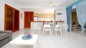 Una sala de estar moderna con comedor, cocina y un balcón con cortinas azules.