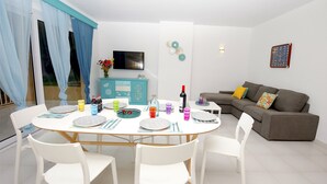 Comedor con una mesa redonda dispuesta para cuatro, sillas blancas y un mueble azul al fondo.