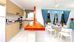 Una cocina moderna con armarios de madera, una zona de comedor con mesa y sillas, y un ventilador de techo.