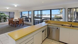 A modern kitchen with large windows, a dining area, and a view of the outdoors. - The Escape (Merimbula)