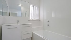 Une salle de bain moderne avec un meuble-lavabo blanc, une douche en verre et un grand miroir.
