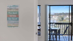 A room with a view of a beach and a sign listing beach names. - The Escape (Merimbula)