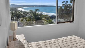 A bedroom with a large window overlooking a beach and ocean. - Seaview Pambula Beach (Pambula Beach)