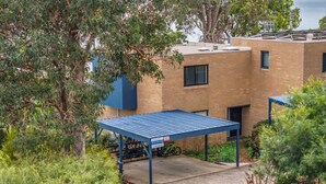 A building with a covered parking area, a bicycle, and surrounding greenery. - Seaview Pambula Beach (Pambula Beach)