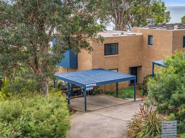 A building with a covered parking area, a bicycle, and surrounding greenery. - Seaview Pambula Beach (Pambula Beach)