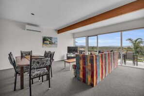 A modern interior with a dining area, a TV, and a balcony with a view.
