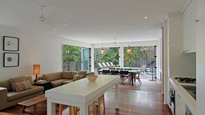 Un salon moderne avec une table à manger blanche, un canapé et un coin cuisine équipé d’une cuisinière.