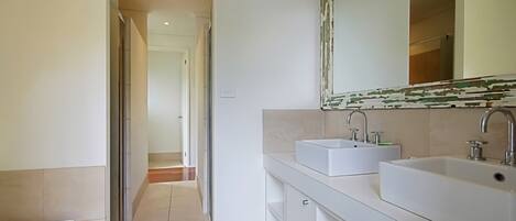 Un baño moderno con dos lavamanos, un espejo grande y una zona de ducha.