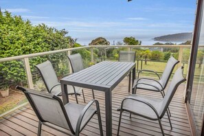 Eine Terrasse mit Tisch und Stühlen mit Blick auf eine Küstenlandschaft.