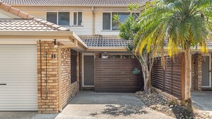 A two-story house with a garage, a brick wall, and a palm tree. - Byron Bay Accom - Eastpoint 2 - 18 - 20 Paterson Lane (Byron Shire)