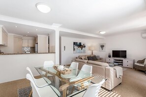 Relax in this stylish living space with a glass-top dining table, comfortable sofa, and flat-screen TV.