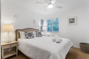 Cozy retreat with a single bed, ceiling fan, and a window with blinds.