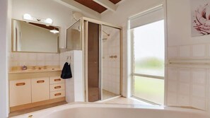 Ein Badezimmer mit Badewanne, Dusche, Waschtisch und Spiegel sowie einem Fenster.