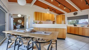 Eine moderne Küche mit Holzschränken, einer Kochinsel und einem Essbereich mit Tisch und Stühlen.