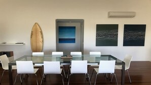 Una sala de reunions moderna amb taula de vidre, cadires blanques, una taula de surf i obra d'art abstracta a les parets.