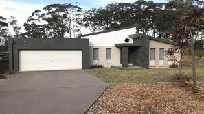 A modern two-story house with a garage, a stone facade, and a well-maintained lawn. - Turaroo (Tura Beach)