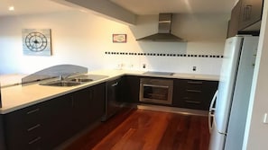 Una cocina moderna con refrigerador de acero inoxidable, pileta doble, horno y salpicadero de azulejos blanco y negro.