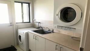 Un cuarto de lavandería con lavadora, lavabo y secadora.