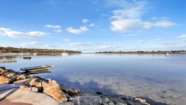 A calm lake with boats, clear water, and rocky shore.