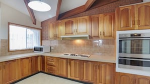 Cozinha com armários de madeira, micro-ondas, fogão e forno.