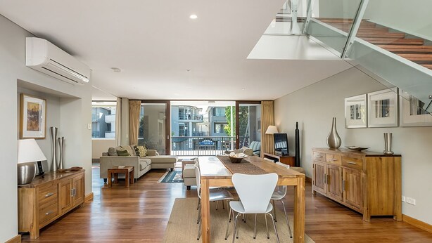 Uma sala de estar moderna com área de jantar, piso de madeira e escada.