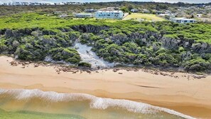 Une propriété située sur la côte, dotée d’une plage, d’une végétation luxuriante et de plusieurs bâtiments.