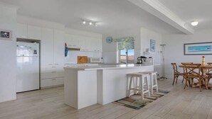Een moderne keuken met witte kasten, een centraal eiland en een eetgedeelte met houten stoelen.