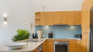 Eine moderne Küche mit Holzschränken, einer weißen Arbeitsplatte, einem Spülbecken, einem Herd und einem Kühlschrank.