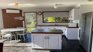 A kitchen with white cabinets, a wooden countertop, a refrigerator, and a dining area with a table and chairs.