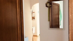 A hallway with a wooden door, a white wall, and a tiled floor. - Budoni Villetta EDDY between sea and nature (budoni)