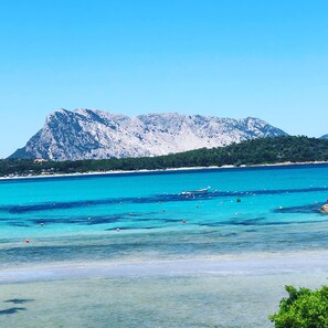 A coastal landscape with a mountain, clear blue sea, and a boat. - Budoni Villetta EDDY between sea and nature (budoni)