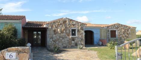 A stone building with a tiled roof, a stone entrance, and a small window.