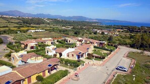 A residential area with houses featuring red-tiled roofs, surrounded by greenery and a clear view of the sea and mountains in the background. - Budoni Villetta EDDY between sea and nature (budoni)
