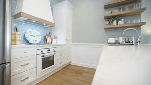 Eine moderne Küche mit weißen Schränken, einem eingebauten Ofen und einer Arbeitsplatte mit Wasserkocher und Toaster.