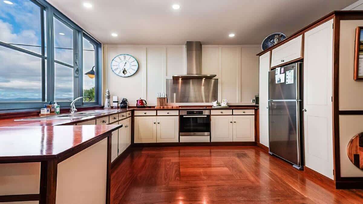 A kitchen with a large window, stainless steel appliances, and wooden flooring.