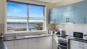 A kitchen with a large window, stainless steel appliances, and light blue cabinets.