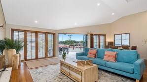 Amplia sala de estar con un sofá azul, una mesa de centro de madera y grandes puertas correderas de vidrio que dan a un patio exterior.