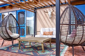 A patio area with two hanging chairs, a wooden table, and a white sofa. - Santa Fe Desert Adobe Retreat - Mountain Views (Santa Fe)