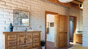Een kamer met een houten dressoir, een kunstwerk aan de muur en een deur naar een andere kamer.