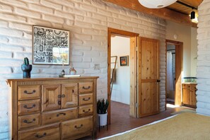 A room with a wooden dresser, a wall-mounted artwork, and a door leading to another room. - Santa Fe Desert Adobe Retreat - Mountain Views (Santa Fe)