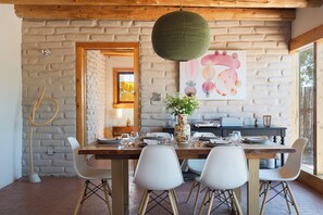 A dining area with a brick wall, a wooden ceiling, and a table set for four. - Santa Fe Desert Adobe Retreat - Mountain Views (Santa Fe)