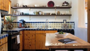 Een keuken met houten kasten, een betegelde spatwand, een koffieapparaat en een fruitschaal op het aanrecht.