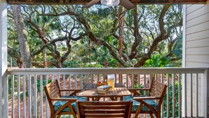 A wooden deck with a table and chairs, overlooking a lush garden with large trees. - GREAT Central Resort Location! Walk to Amenities! Community Pool! (Isle Of Palms)