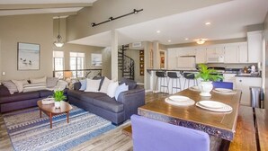 A modern living room with a sofa set, a dining table with placemats, and a kitchen area with white cabinets and a bar stool. - 4 Outdoor Areas * A/C * 5 Parking * 3 Levels * Dog OK (San Diego)