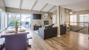 A spacious living area with a wooden floor, a dining table set with plates, a sofa, and a TV mounted on the wall. - 4 Outdoor Areas * A/C * 5 Parking * 3 Levels * Dog OK (San Diego)